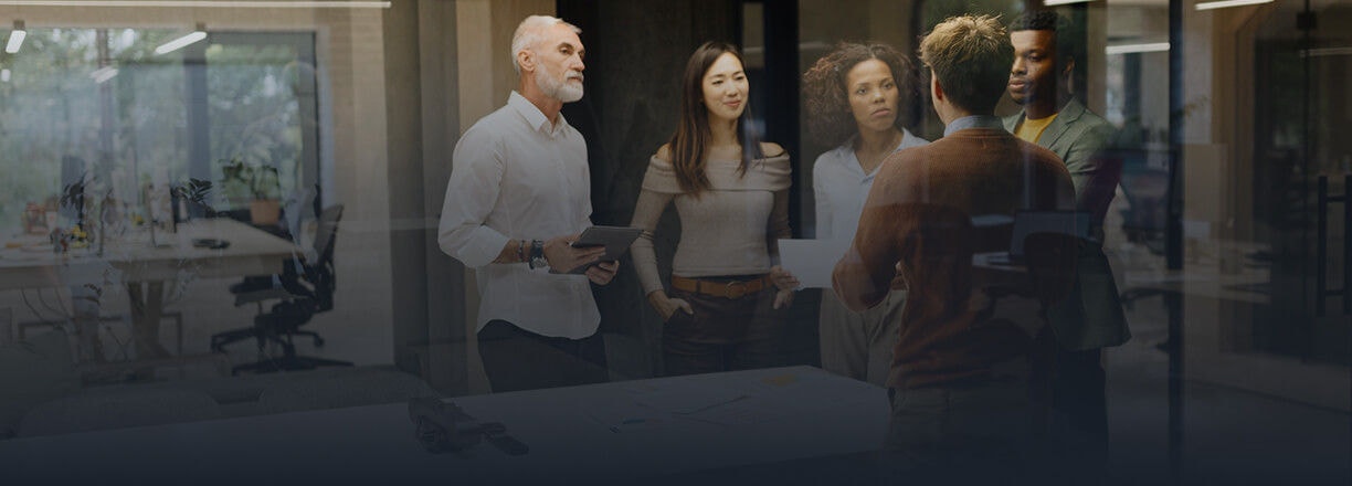 Um grupo de colegas a discutir um projeto à volta de uma mesa num escritório moderno.