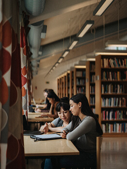 Alunos a estudar juntos numa mesa numa biblioteca.